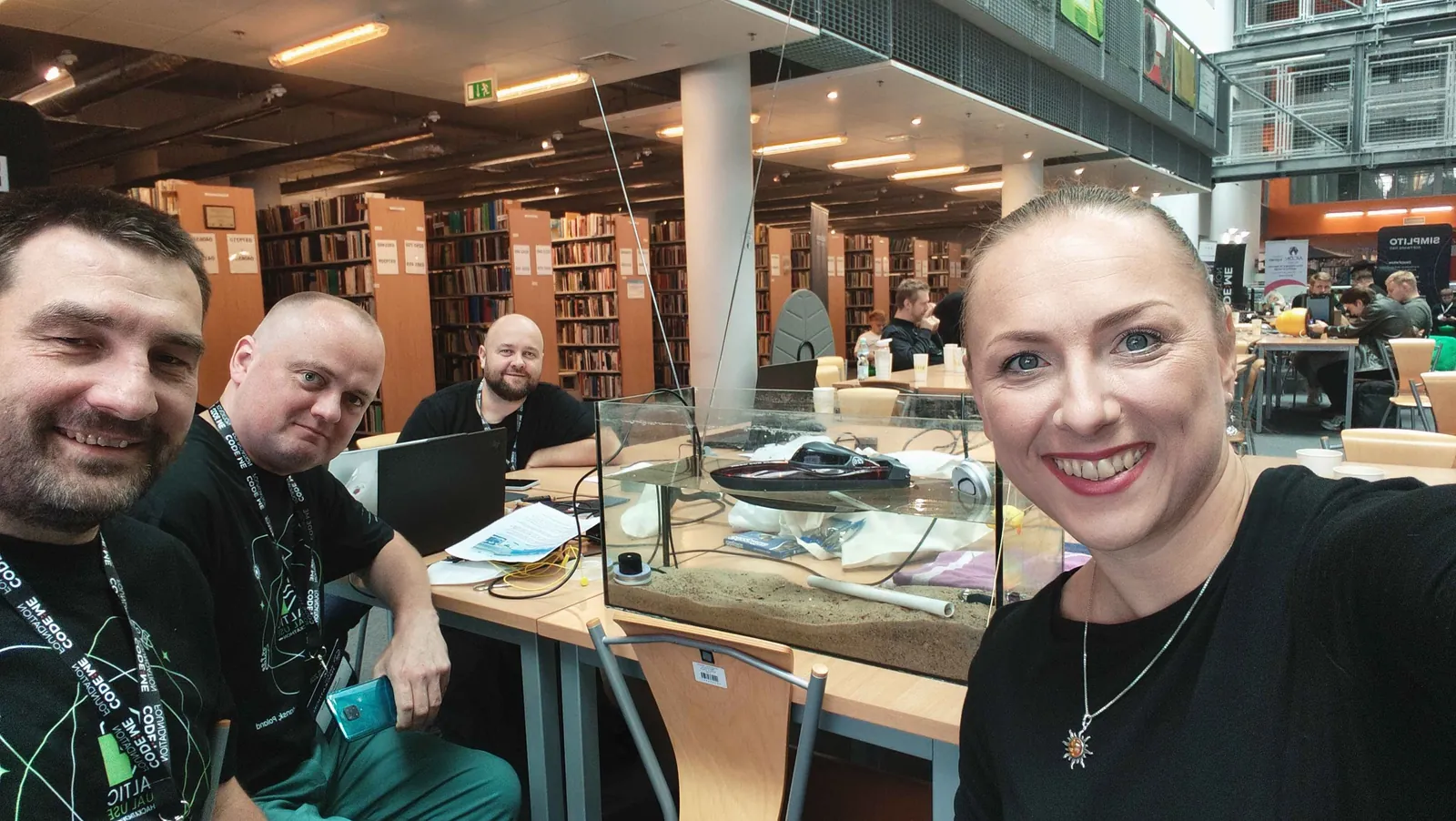 Zespół OTOLITH przy stole w bibliotece, obok akwarium z piaskiem, rurą i modelem motorówki