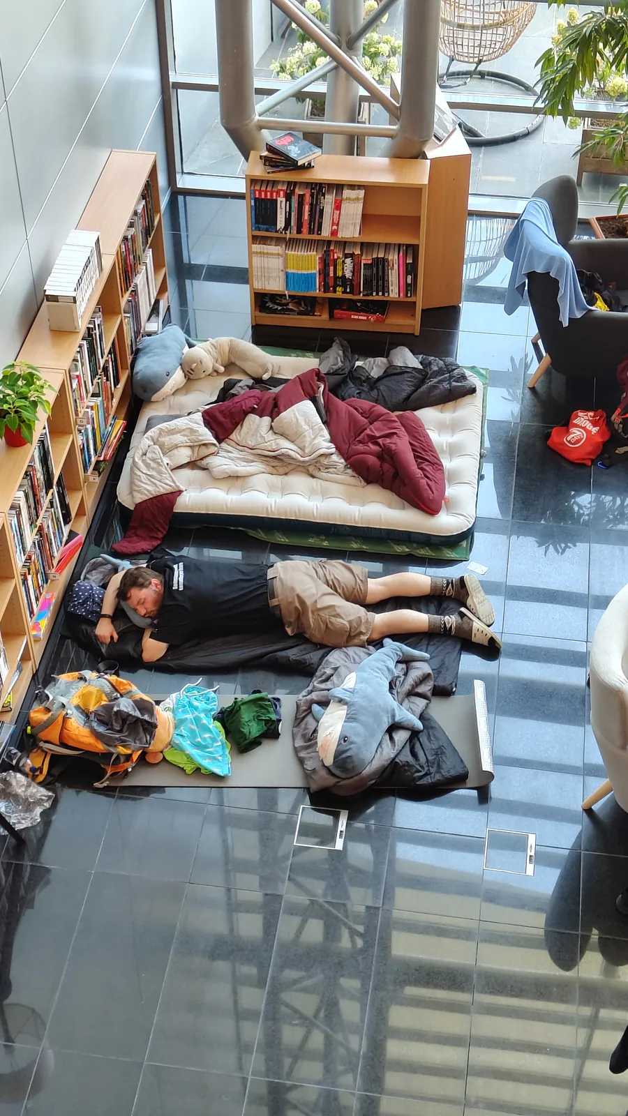 Uczestnicy hackathonu śpiący na materacach między regałami z książkami