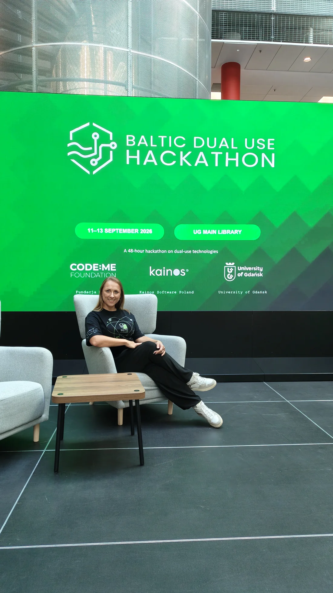 Olimpia Goździewicz na fotelu przed ekranem z logo Baltic Dual Use Hackathon