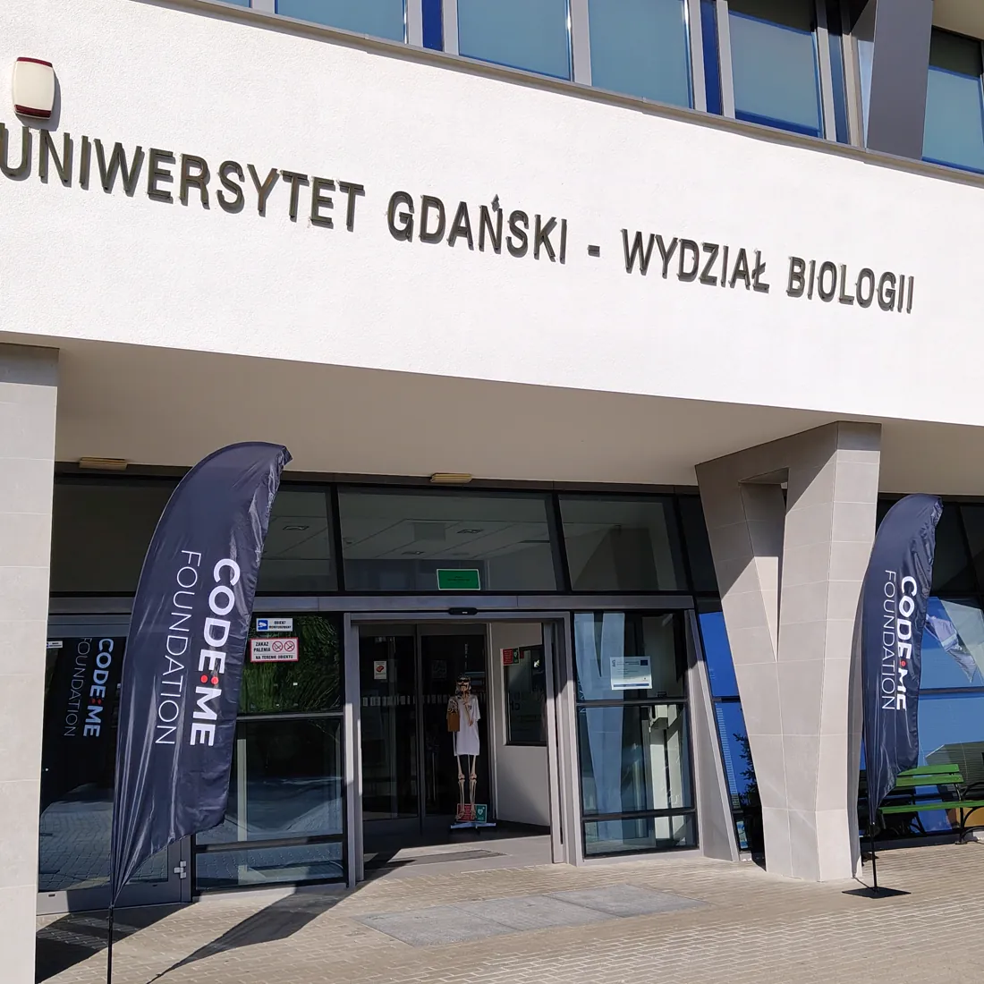 Wejście na Wydział Biologii Uniwersytetu Gdańskiego z flagami CODE:ME Foundation