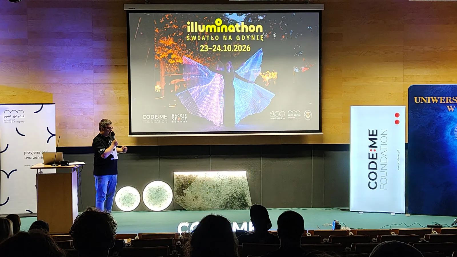 Otwarcie Illuminathonu w Sali Morskiej PPNT: prowadzący na scenie, na ekranie logo Illuminathon, Światło na Gdynię, 23-24.10.2026, publiczność na widowni