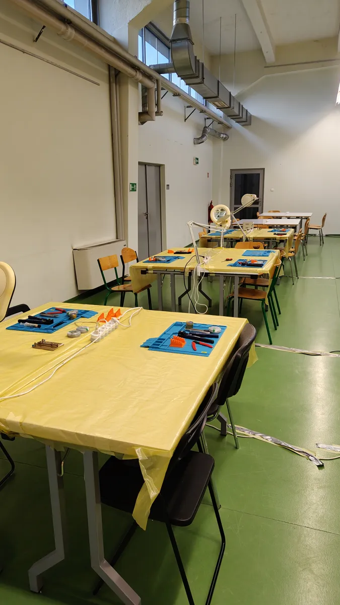 Pusta sala przed startem hackathonu, stoły przykryte żółtym papierem, przygotowane stanowiska