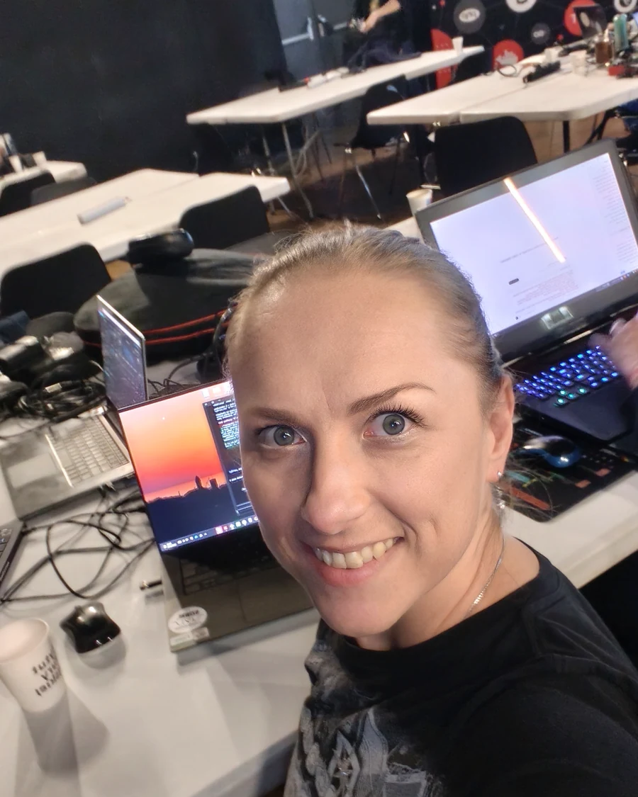 Olimpia Goździewicz przy stanowisku pracy, w tle laptopy i sprzęt innych uczestników